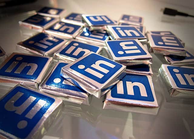 A pile of small, square chocolates wrapped in foil, each featuring the blue and white LinkedIn logo on top, arranged on a white surface&mdash;perfect for celebrating social media trends.