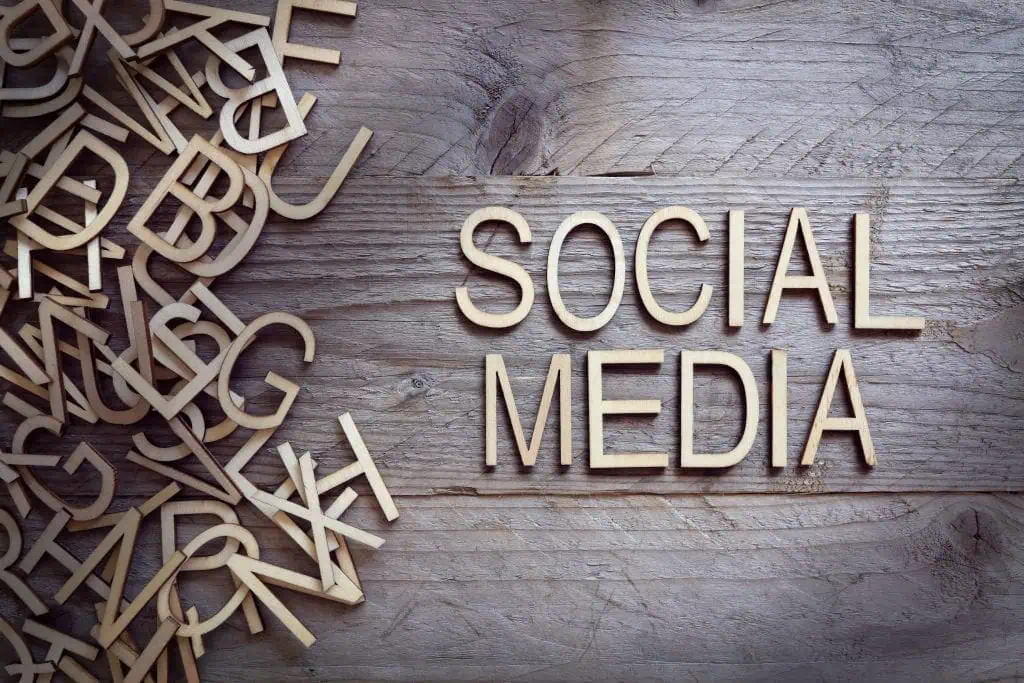 Wooden letters scattered on a rustic wooden surface, with the words SOCIAL MEDIA—highlighting current social media trends—neatly arranged on the right side.