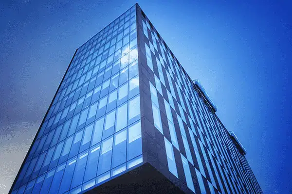 Office building with glass facade reflecting sunlight and sky.